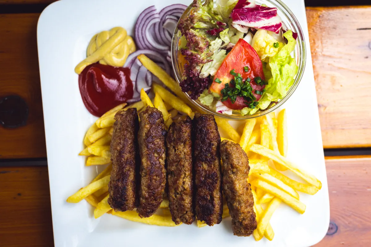 Plato de ćevapi con patatas fritas y ensalada