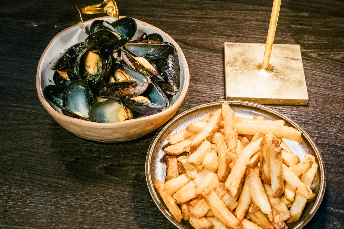 Un plato de mejillones con patatas fritas