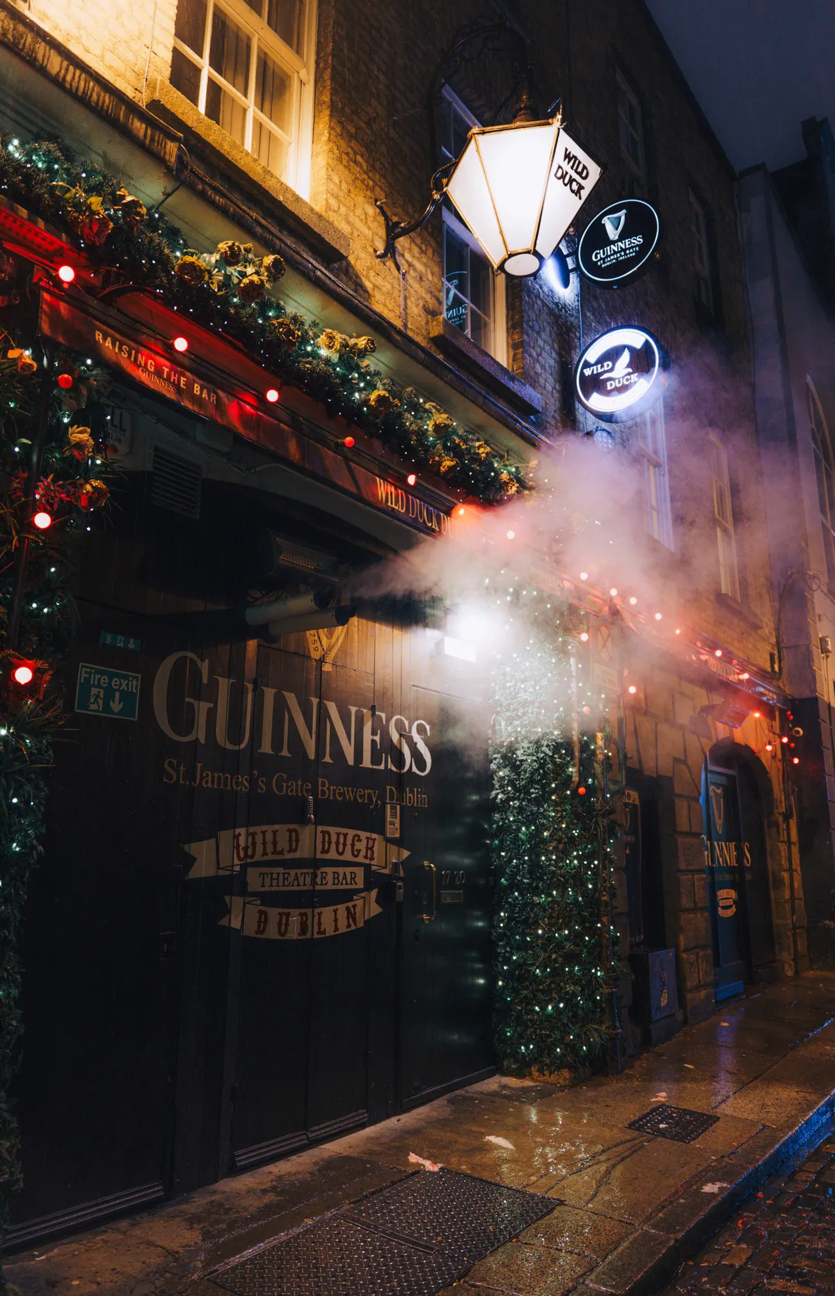 Fachada de un pub de Dublín iluminada de noche con el letrero de Guinness